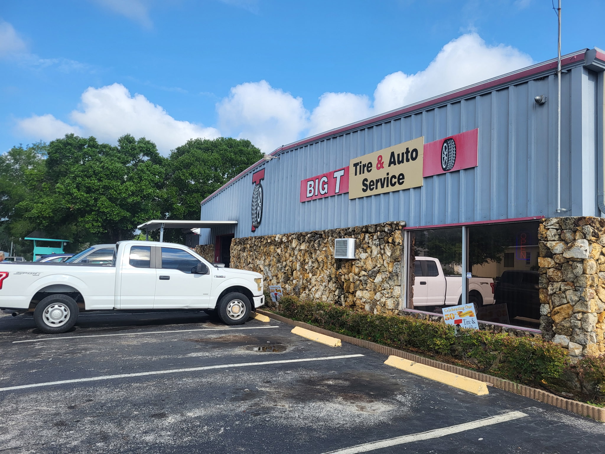 Side storefront view of Big T Tire and Auto Service sign