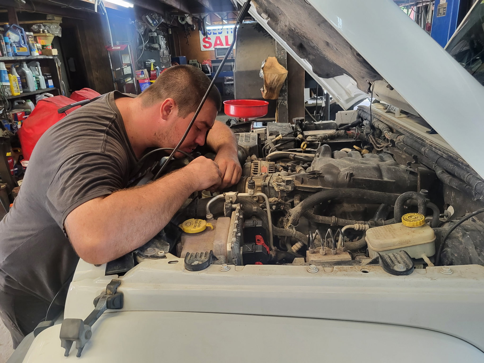 Big T technician working under the hood on a vehicle in the shop