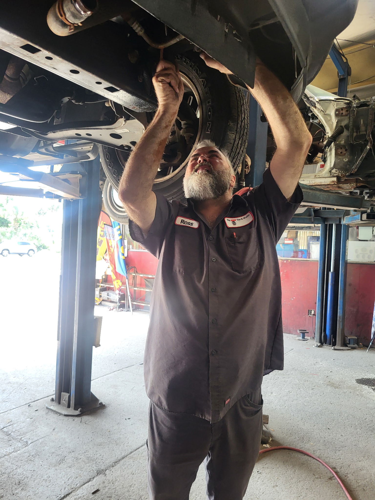Big T technician servicing the underside of a vehicle on a lift